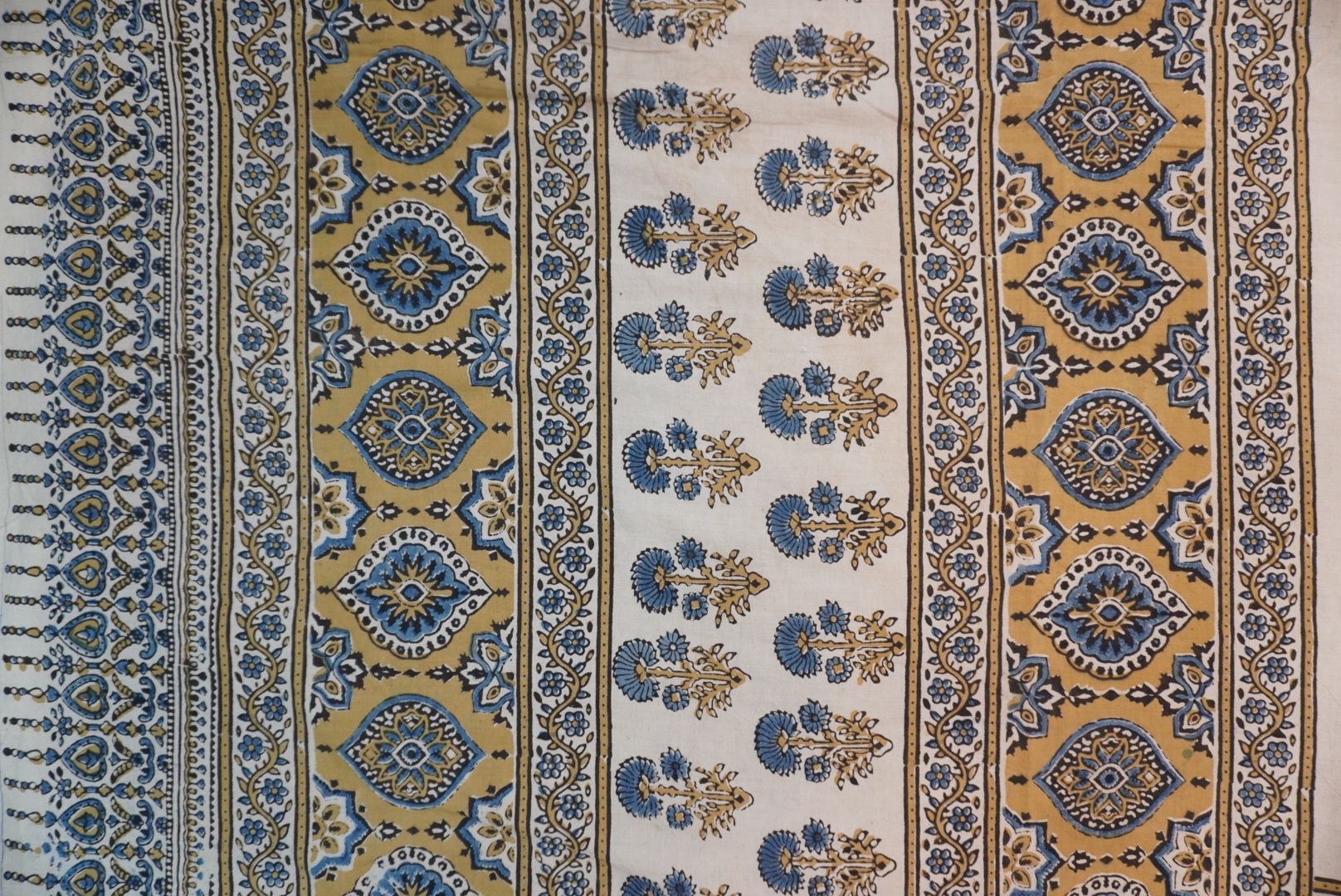 Ivory cotton Ajrakh saree with olive green, blue and yellow block print, border and tassels