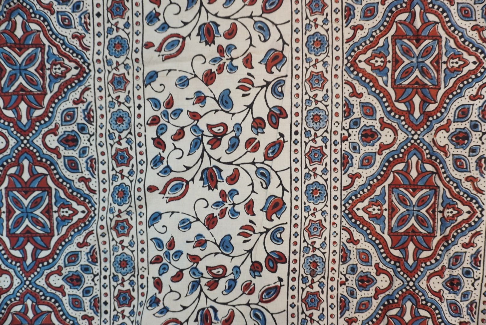 Ivory cotton Ajrakh saree with red, blue and rust placement pattern, border and tassels