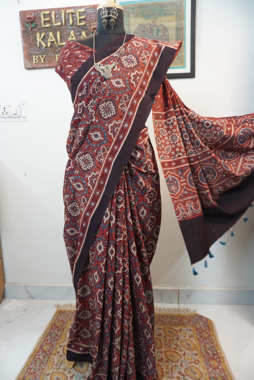 Rust red cotton Ajrakh saree with all-over multicolour pattern, border and tassels