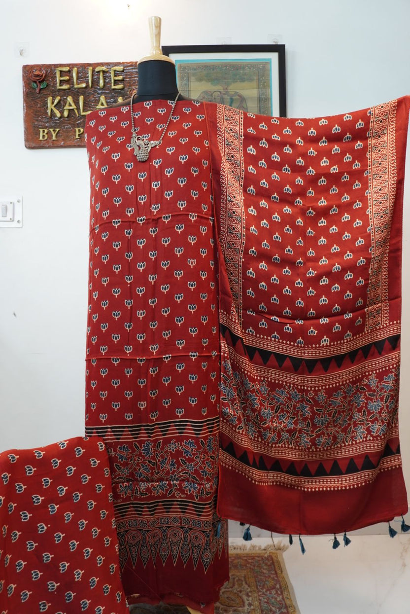 Red 3 piece suit with stole, multicolor placement pattern and small lotus design with border and tassels