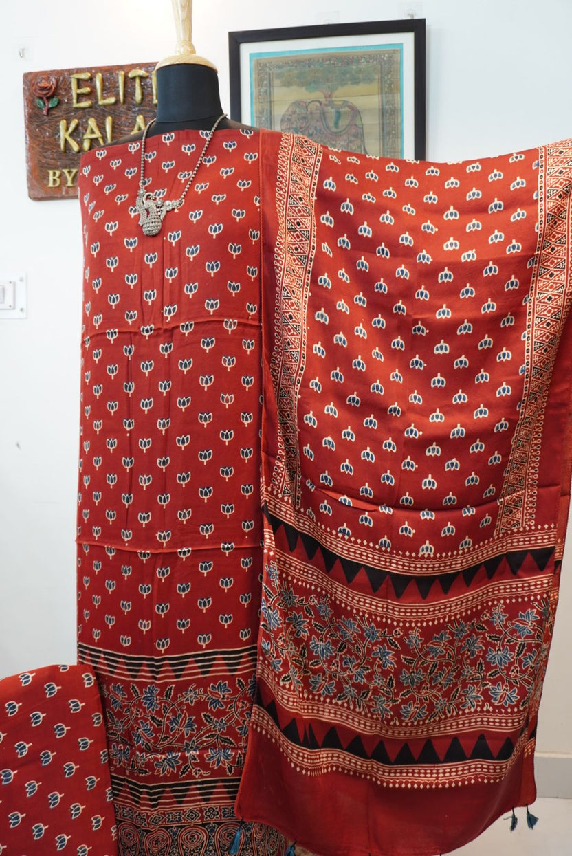 Red 3 piece suit with stole, multicolor placement pattern and small lotus design with border and tassels