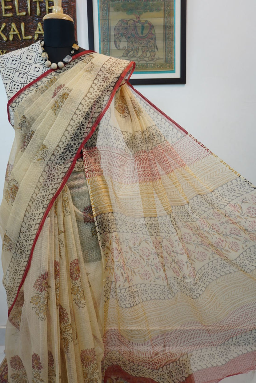 Cream saree with all-over multicolor design in red, black, yellow and brown and a border