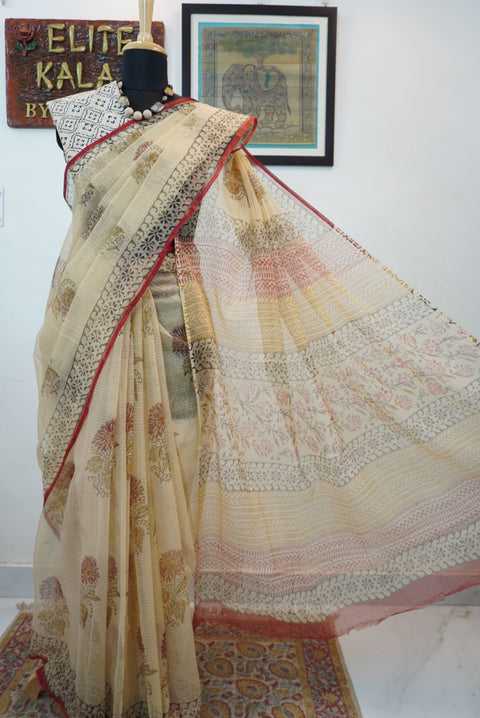 Cream saree with all-over multicolor design in red, black, yellow and brown and a border