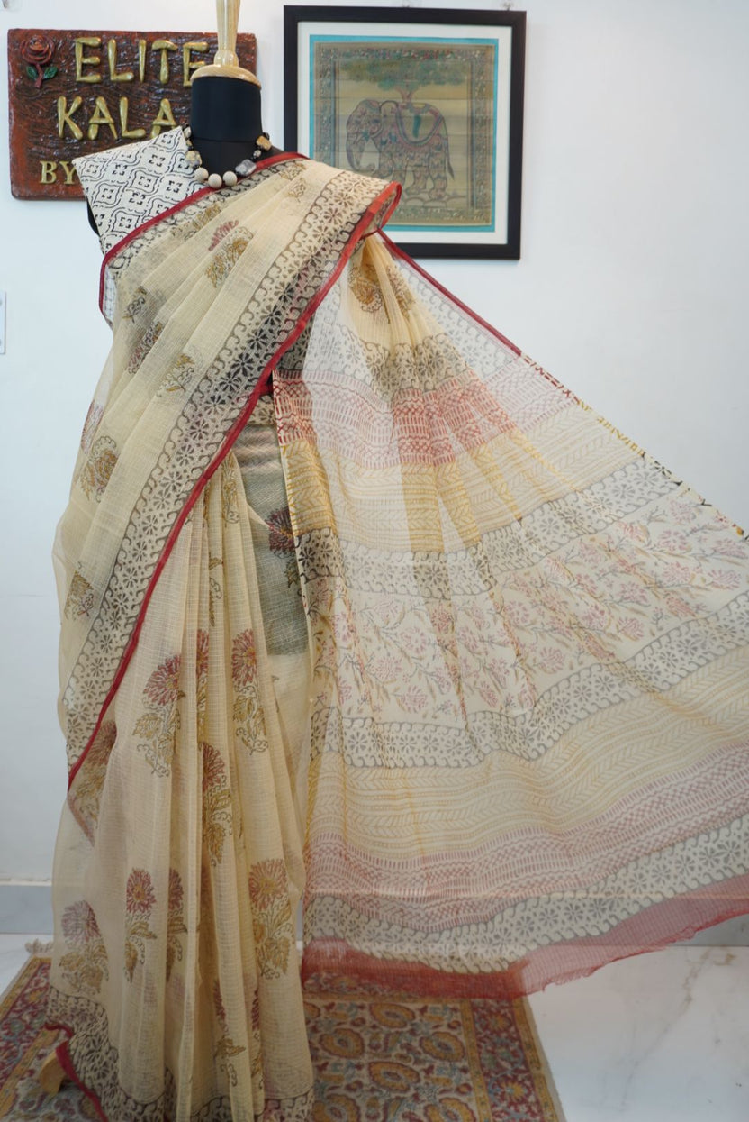 Cream saree with all-over multicolor design in red, black, yellow and brown and a border