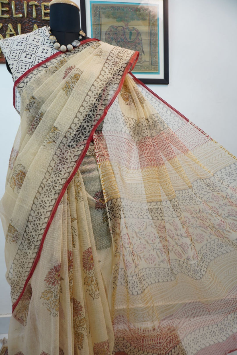 Cream saree with all-over multicolor design in red, black, yellow and brown and a border